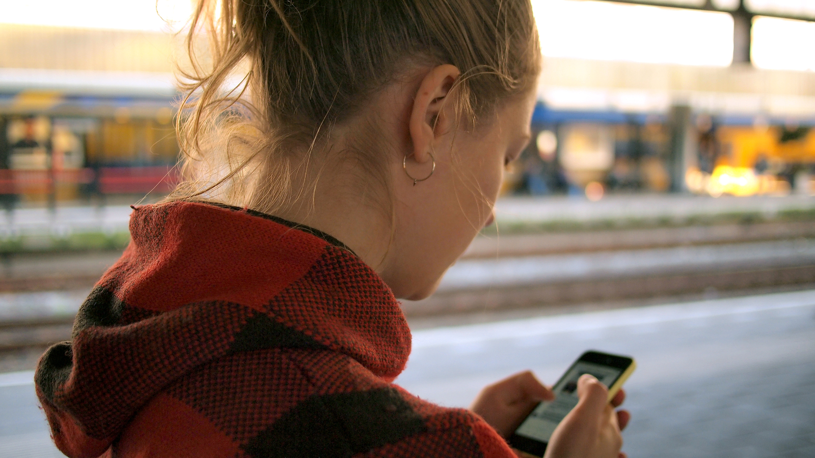 Utazó ellenőrzi a telefonját vasútállomáson — eSIM kompatibilitás ellenőrzése
